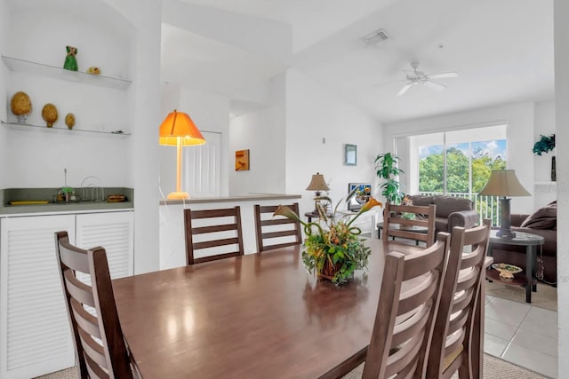 dining room with ceiling fan, light tile patterned floors, and vaulted ceiling