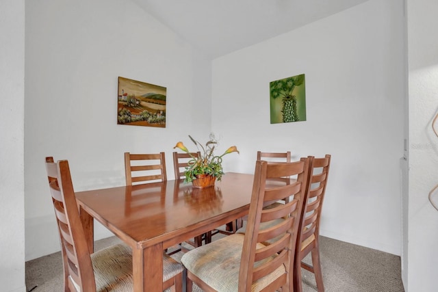 carpeted dining area with vaulted ceiling