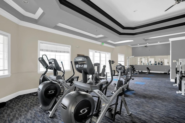 exercise room featuring a raised ceiling, dark carpet, and crown molding