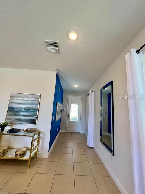 interior space with light tile patterned flooring and a textured ceiling