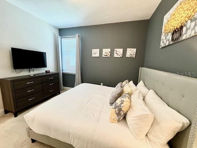 bedroom featuring light carpet and baseboards