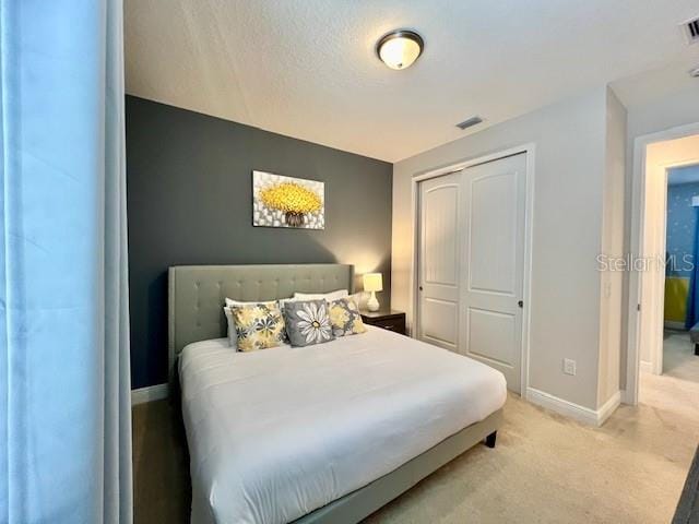 bedroom with visible vents, baseboards, a closet, and light colored carpet