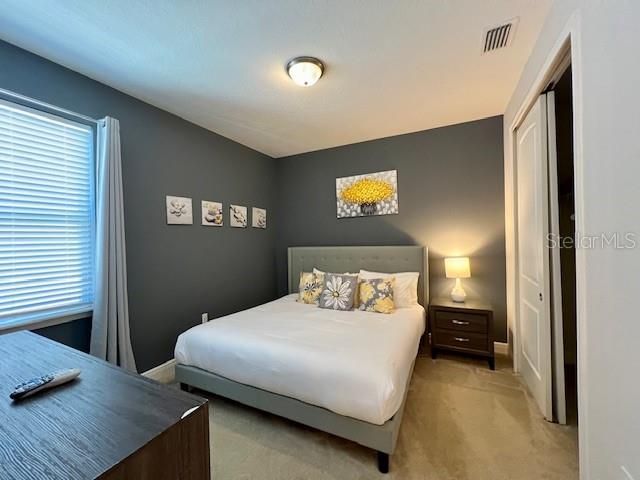 bedroom featuring light colored carpet, visible vents, and baseboards