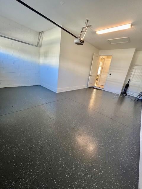 garage featuring concrete block wall and a garage door opener