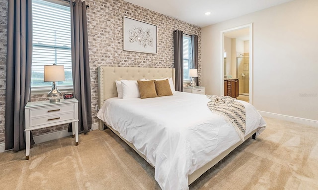 bedroom featuring light carpet, ensuite bath, baseboards, and multiple windows