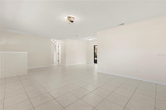 spare room featuring a textured ceiling and light tile patterned floors