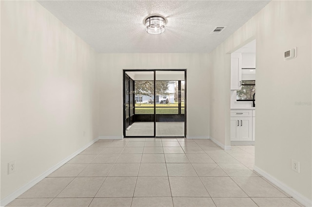 tiled empty room featuring a textured ceiling