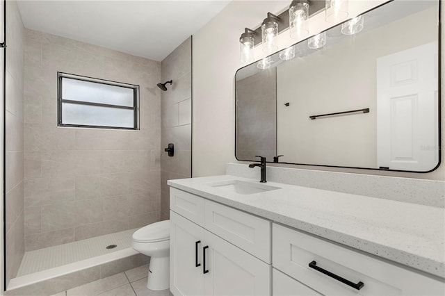 bathroom featuring vanity, tile patterned floors, toilet, and tiled shower