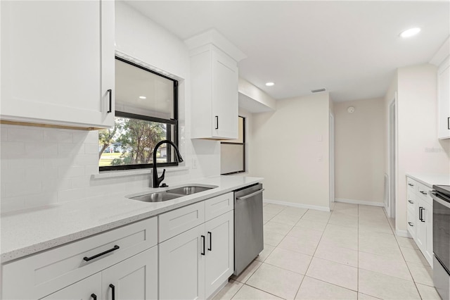 kitchen with light tile patterned flooring, sink, appliances with stainless steel finishes, light stone countertops, and white cabinets