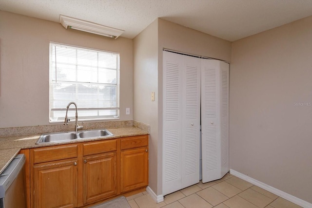 kitchen featuring sink, light tile patterned flooring, stainless steel dishwasher, and a textured ceiling