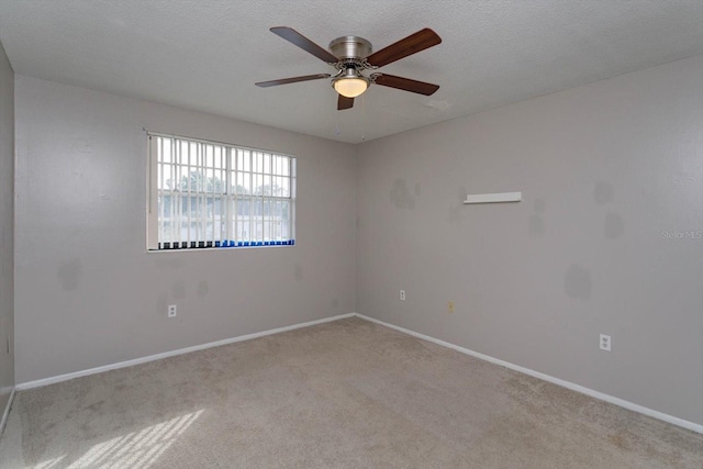 spare room featuring ceiling fan, light carpet, and a textured ceiling