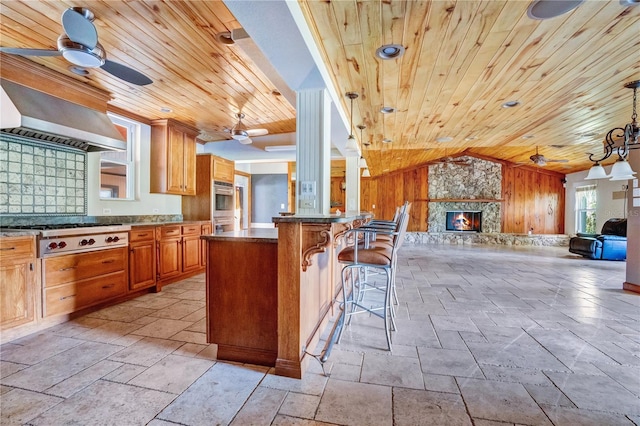 kitchen featuring a kitchen bar, wood ceiling, a fireplace, and wood walls