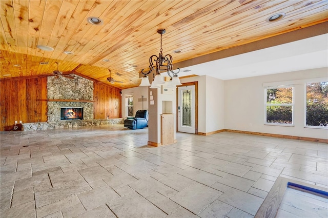 unfurnished living room featuring a chandelier, lofted ceiling, wooden walls, a fireplace, and wood ceiling