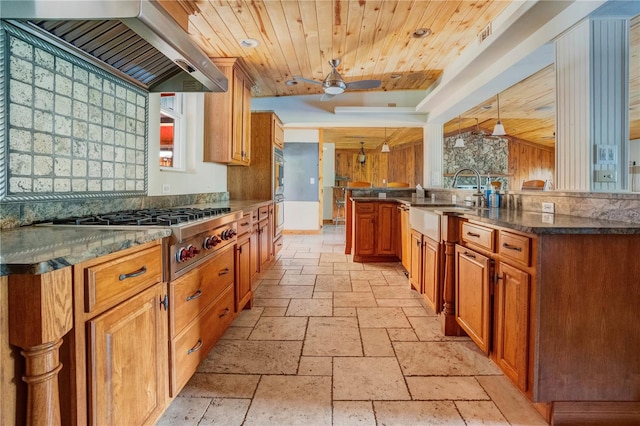 kitchen featuring pendant lighting, wall chimney range hood, vaulted ceiling, ceiling fan, and kitchen peninsula