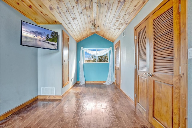 hall featuring hardwood / wood-style floors, wooden ceiling, and vaulted ceiling