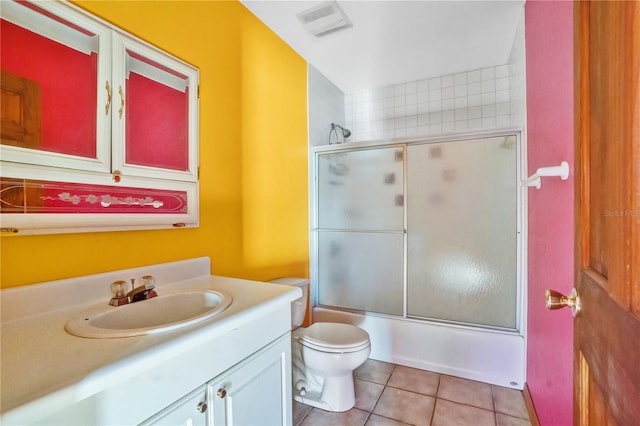 full bathroom featuring tile patterned flooring, vanity, toilet, and bath / shower combo with glass door