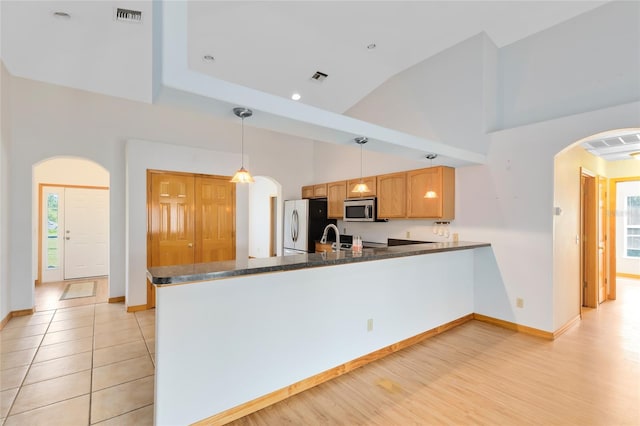 kitchen featuring appliances with stainless steel finishes, pendant lighting, lofted ceiling, sink, and kitchen peninsula