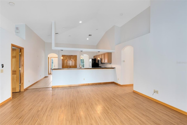 unfurnished living room featuring vaulted ceiling and light hardwood / wood-style flooring