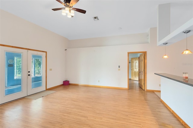 unfurnished room with french doors, ceiling fan, a towering ceiling, and light wood-type flooring