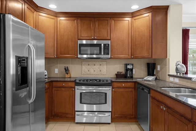 kitchen with stainless steel appliances, dark stone countertops, light tile patterned floors, and tasteful backsplash