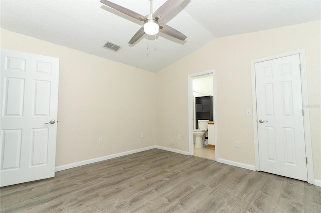 unfurnished bedroom featuring connected bathroom, vaulted ceiling, ceiling fan, and light hardwood / wood-style flooring