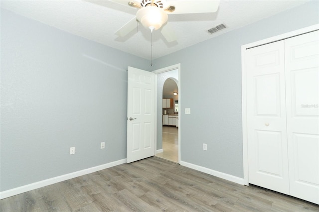 unfurnished bedroom featuring a closet, a textured ceiling, ceiling fan, and light hardwood / wood-style flooring