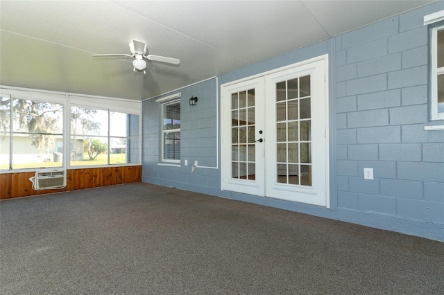 unfurnished sunroom with french doors, a wall unit AC, and ceiling fan