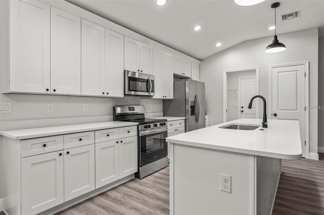 kitchen featuring white cabinets, hanging light fixtures, sink, a kitchen island with sink, and appliances with stainless steel finishes