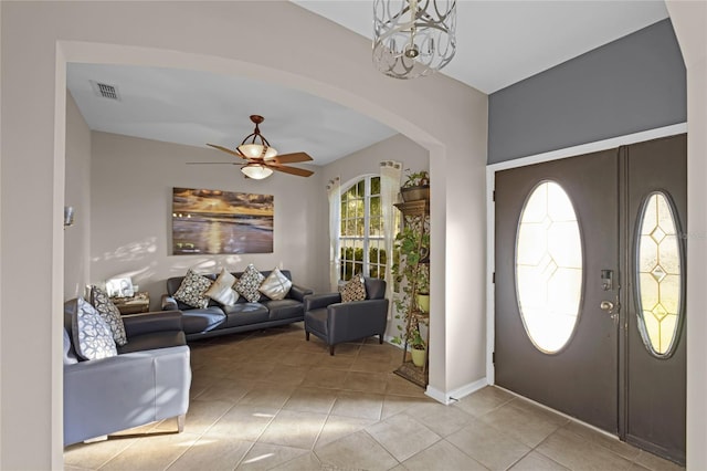 tiled foyer entrance featuring ceiling fan with notable chandelier