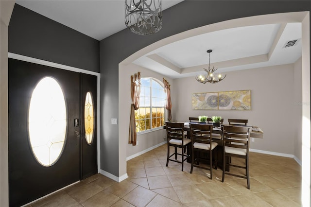 tiled dining space with a tray ceiling and a notable chandelier