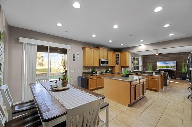 kitchen featuring tasteful backsplash, stainless steel appliances, light tile patterned floors, kitchen peninsula, and a center island