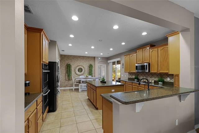 kitchen with stainless steel appliances, a kitchen bar, dark stone countertops, and kitchen peninsula