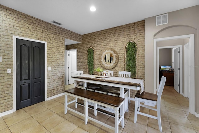 dining area with brick wall and light tile patterned flooring