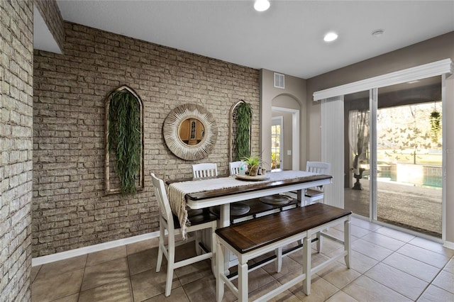 dining area featuring brick wall, a healthy amount of sunlight, and light tile patterned floors