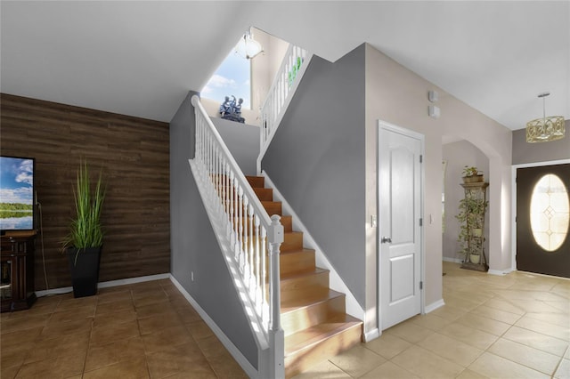 entrance foyer with wood walls, a chandelier, and light tile patterned floors