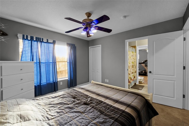 tiled bedroom with a textured ceiling, ensuite bath, ceiling fan, and a closet