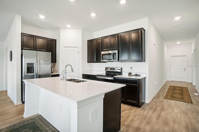 kitchen featuring light hardwood / wood-style floors, sink, a kitchen island with sink, and appliances with stainless steel finishes