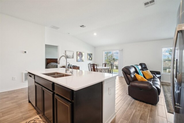 kitchen featuring light wood-type flooring, sink, vaulted ceiling, and a kitchen island with sink