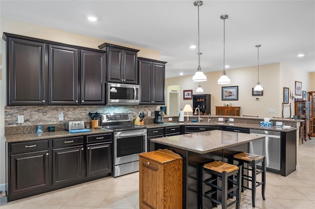 5307 Cortland Dr, Davenport, FL 33837 - kitchen with stainless steel appliances, a peninsula, a center island, light tile patterned floors, and backsplash