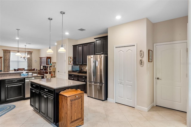 5307 Cortland Dr, Davenport, FL 33837 - kitchen with appliances with stainless steel finishes, dark cabinetry, a kitchen island, light stone countertops, and pendant lighting
