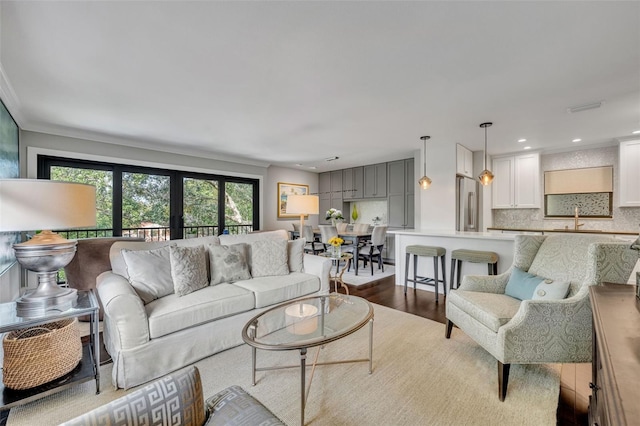 living room featuring light hardwood / wood-style floors, ornamental molding, and sink