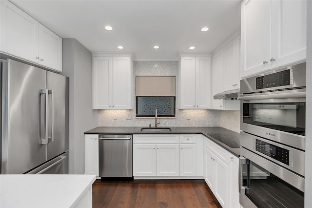 kitchen with dark hardwood / wood-style flooring, tasteful backsplash, stainless steel appliances, sink, and white cabinetry