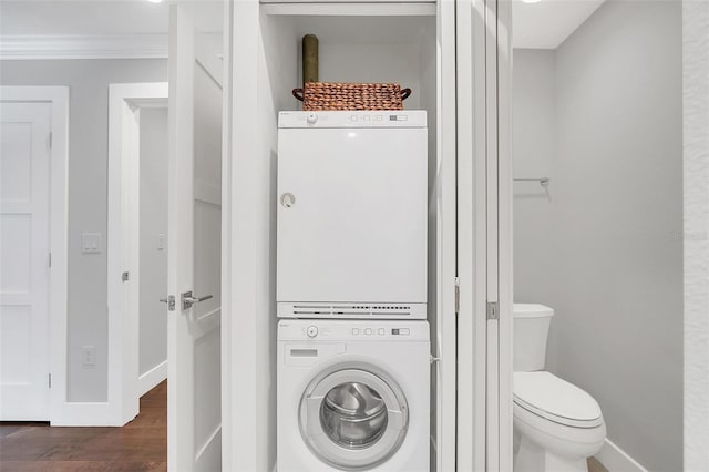 interior space featuring wood-type flooring, stacked washing maching and dryer, toilet, and ornamental molding