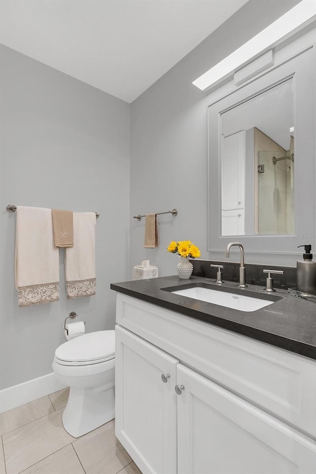 bathroom featuring tile patterned floors, vanity, a shower with shower door, and toilet