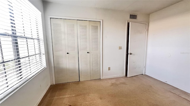 unfurnished bedroom featuring a closet, multiple windows, and light colored carpet