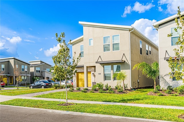 multi unit property featuring a garage and a front lawn