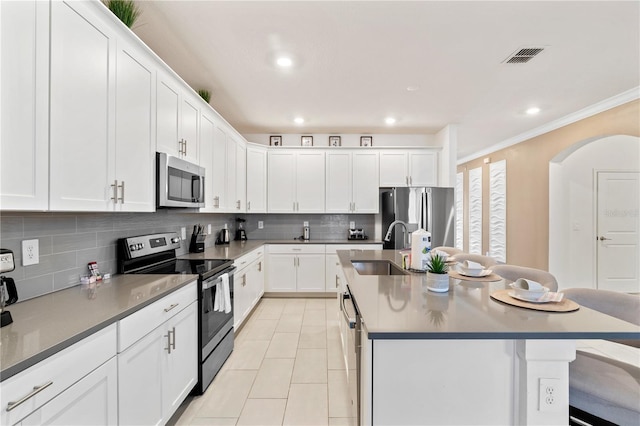 kitchen with stainless steel appliances, sink, white cabinets, a breakfast bar area, and an island with sink