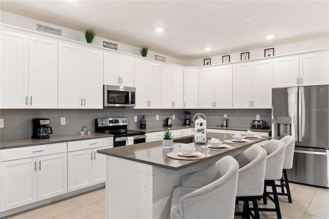 kitchen featuring a kitchen bar, stainless steel appliances, and white cabinetry