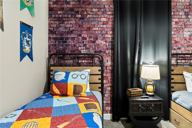 bedroom with carpet floors and brick wall