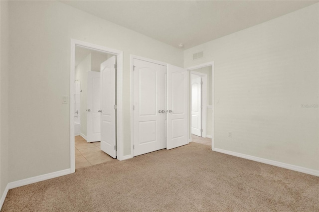 unfurnished bedroom featuring light carpet and a closet